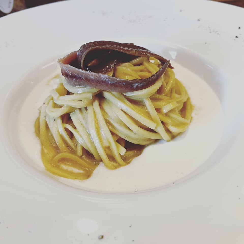 Tagliolini burro e acciughe in un piatto fondo bianco